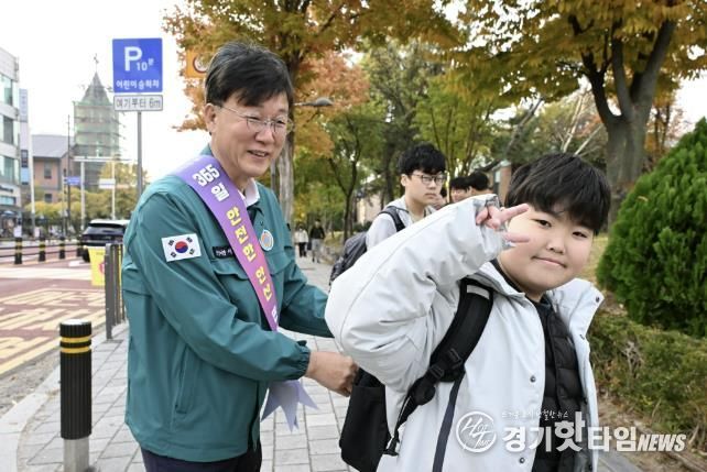 이민근 안산시장(사진 왼쪽)이 학현초등학교 앞에서 ‘스쿨존 어린이 교통안전 캠페인’을 진행하며 등교하는 어린이의 가방에 '홍이 키링'을 달아주고 있다.